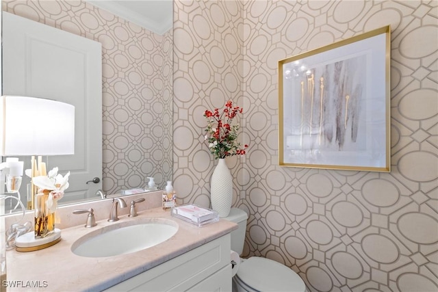 bathroom featuring crown molding, vanity, toilet, and wallpapered walls