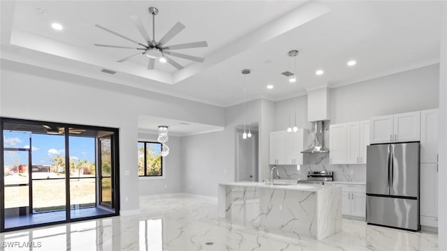 kitchen with marble finish floor, a sink, appliances with stainless steel finishes, wall chimney range hood, and a raised ceiling