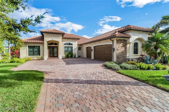 mediterranean / spanish-style house with a garage, a tile roof, decorative driveway, french doors, and stucco siding