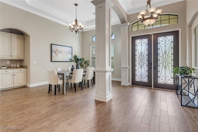 foyer featuring french doors, ornate columns, an inviting chandelier, wood tiled floor, and baseboards