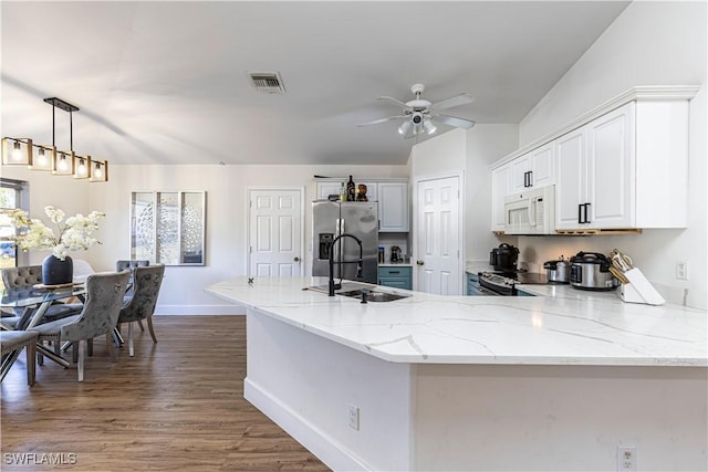 kitchen featuring sink, light stone counters, stainless steel fridge with ice dispenser, hanging light fixtures, and white cabinets