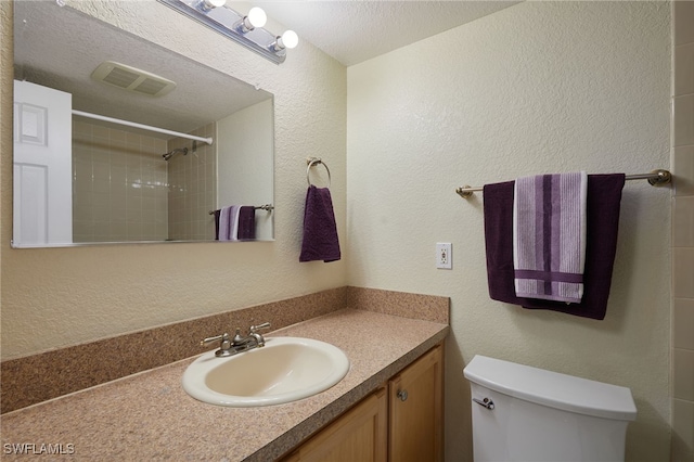 bathroom featuring vanity, a textured ceiling, and toilet