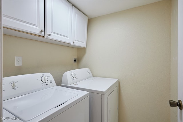 clothes washing area featuring washing machine and dryer and cabinets