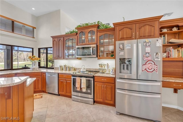 kitchen featuring light stone countertops, appliances with stainless steel finishes, sink, and light tile patterned floors