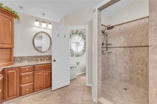 bathroom with vanity, vaulted ceiling, a tile shower, and tile patterned floors