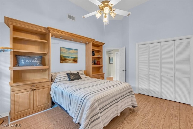 bedroom with ceiling fan, high vaulted ceiling, light hardwood / wood-style floors, and a closet