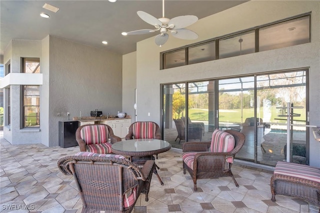 view of patio featuring ceiling fan and glass enclosure