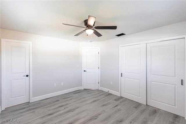 unfurnished bedroom with ceiling fan, a closet, and light wood-type flooring