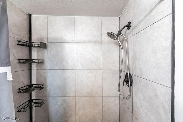 bathroom featuring a textured ceiling and tiled shower