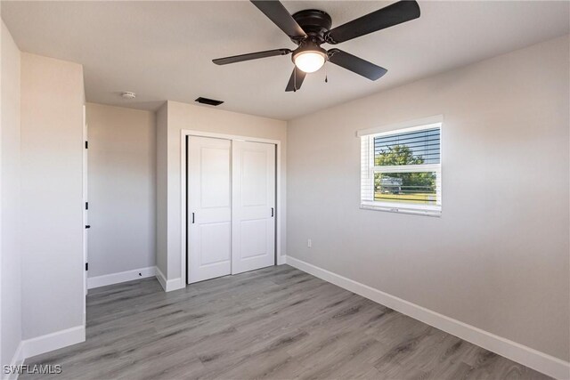 unfurnished bedroom featuring light hardwood / wood-style floors, a closet, and ceiling fan