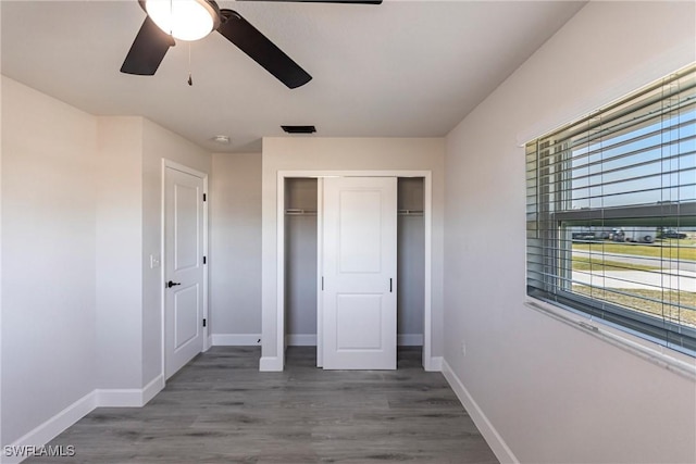 unfurnished bedroom with dark hardwood / wood-style floors, ceiling fan, and a closet