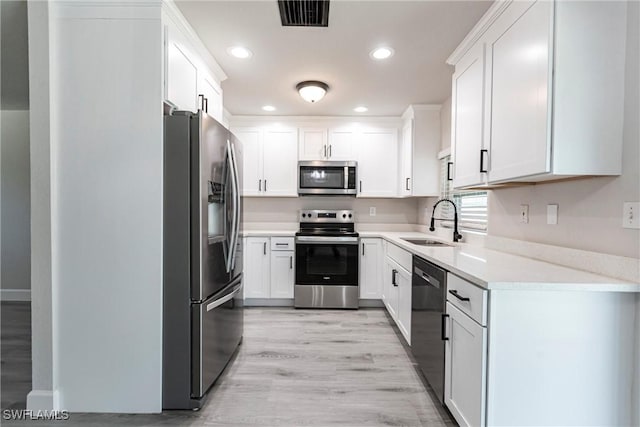 kitchen featuring stainless steel appliances, sink, white cabinets, and light hardwood / wood-style flooring