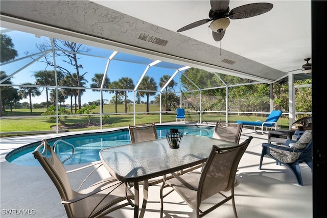 view of swimming pool featuring ceiling fan, a yard, glass enclosure, and a patio area