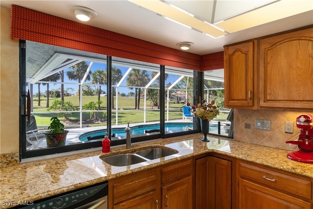 kitchen with tasteful backsplash, light stone countertops, sink, and stainless steel dishwasher