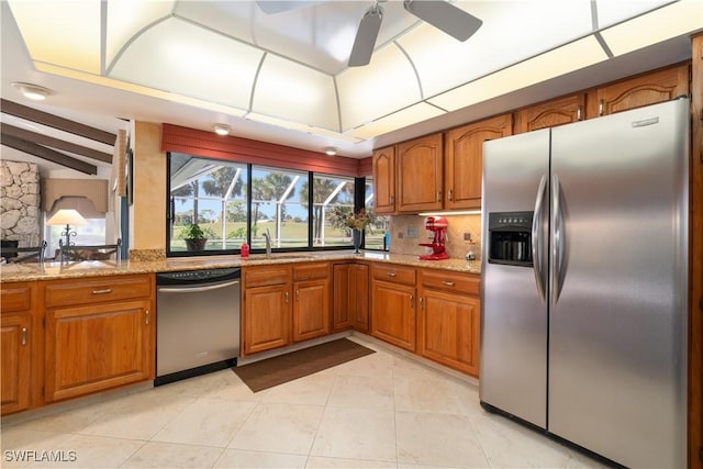 kitchen featuring sink, light stone counters, lofted ceiling with beams, stainless steel appliances, and decorative backsplash