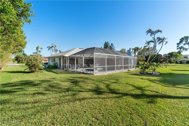 back of property with a lawn and glass enclosure