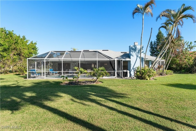 back of house with a lanai and a lawn