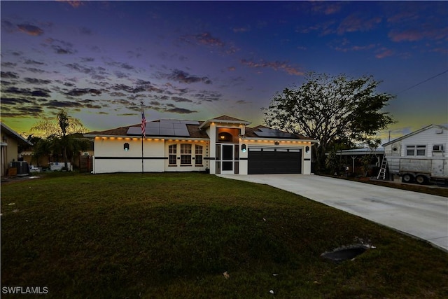 view of front of property with a garage, a lawn, and solar panels