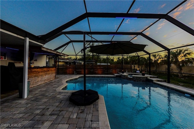 pool at dusk featuring a patio, a lanai, an outdoor bar, and an in ground hot tub