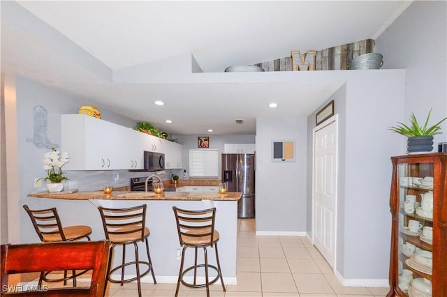 kitchen with stainless steel refrigerator with ice dispenser, white cabinets, a kitchen bar, light tile patterned flooring, and kitchen peninsula