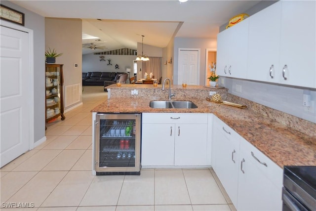 kitchen featuring white cabinets, sink, beverage cooler, and kitchen peninsula