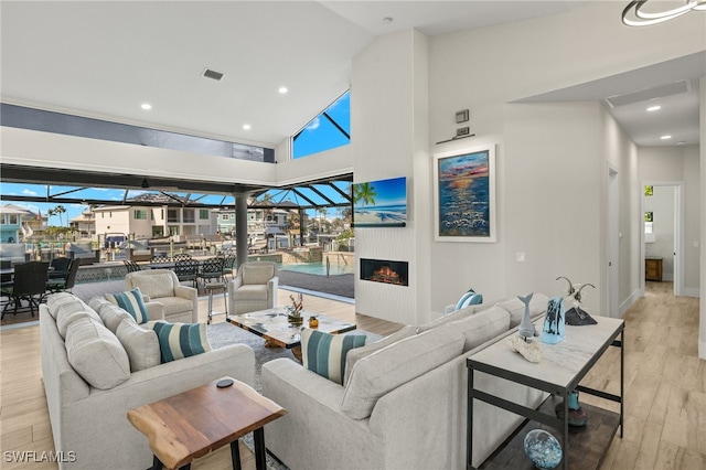 living room with a healthy amount of sunlight, high vaulted ceiling, and light hardwood / wood-style flooring