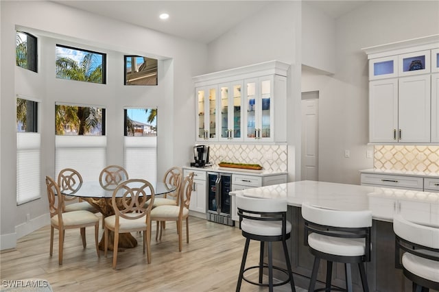 interior space with beverage cooler, a kitchen breakfast bar, light wood-type flooring, and white cabinets