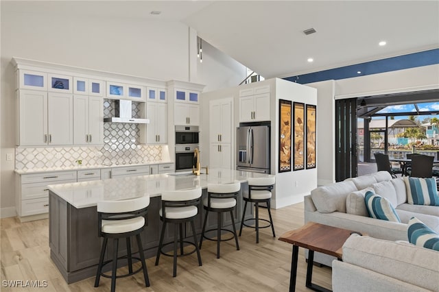 kitchen featuring appliances with stainless steel finishes, a kitchen breakfast bar, an island with sink, and white cabinets