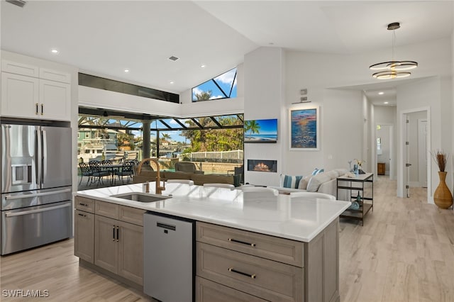 kitchen featuring sink, decorative light fixtures, a center island with sink, light hardwood / wood-style flooring, and appliances with stainless steel finishes