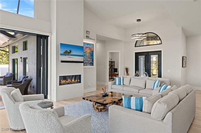 living room featuring plenty of natural light, light hardwood / wood-style flooring, and a high ceiling