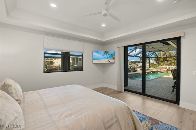 bedroom with a raised ceiling, ceiling fan, access to outside, and light hardwood / wood-style floors