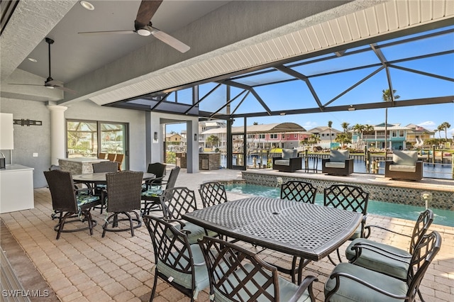 view of pool with glass enclosure, pool water feature, ceiling fan, and a water view