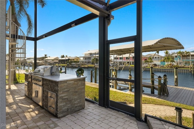 view of patio featuring exterior kitchen, a water view, area for grilling, and a boat dock