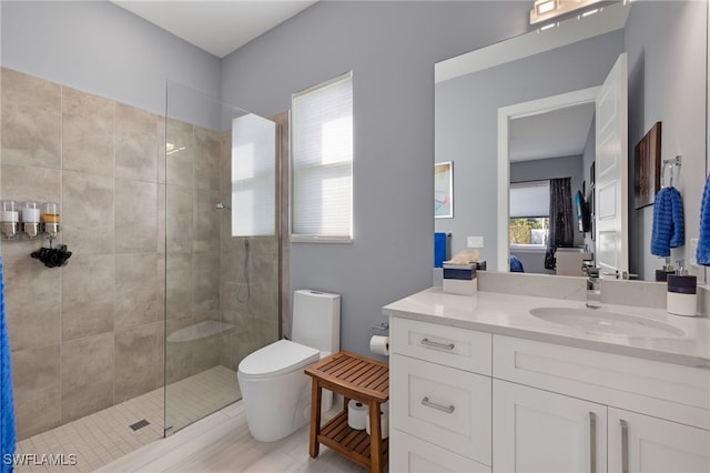 bathroom featuring tiled shower, vanity, and toilet