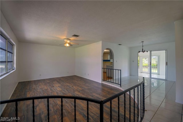 unfurnished room featuring ceiling fan with notable chandelier, a textured ceiling, and light wood-type flooring