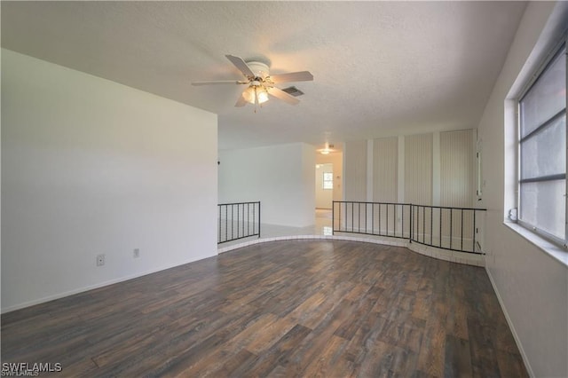 spare room with dark hardwood / wood-style flooring, ceiling fan, and a textured ceiling