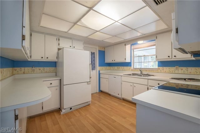 kitchen with white cabinetry, sink, white appliances, and light hardwood / wood-style flooring