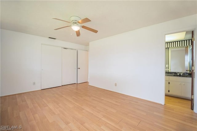 unfurnished bedroom with ensuite bathroom, sink, ceiling fan, light hardwood / wood-style floors, and a closet