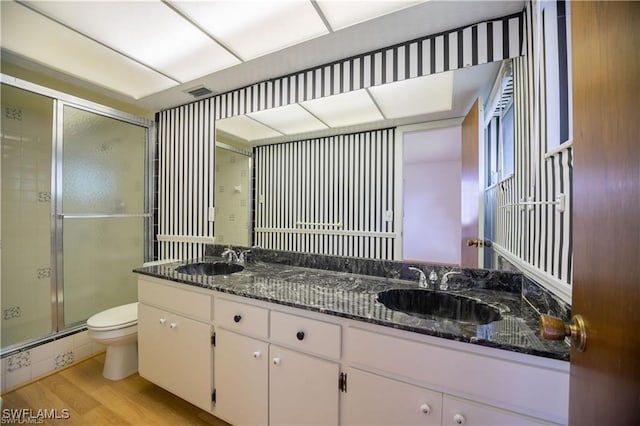 bathroom featuring hardwood / wood-style floors, a baseboard heating unit, vanity, a shower with shower door, and toilet