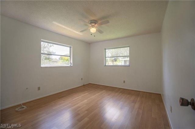 unfurnished room with a textured ceiling, plenty of natural light, ceiling fan, and light wood-type flooring