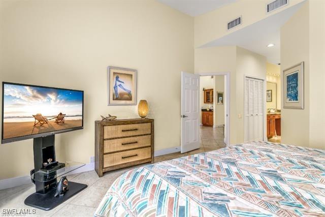 bedroom with a closet, ensuite bath, and light tile patterned floors