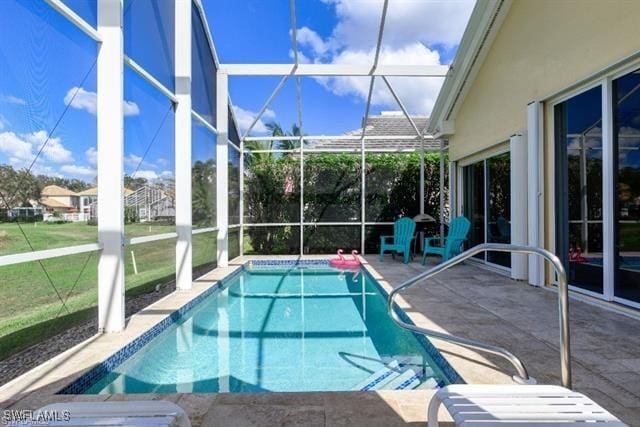 view of swimming pool featuring a yard, glass enclosure, and a patio area