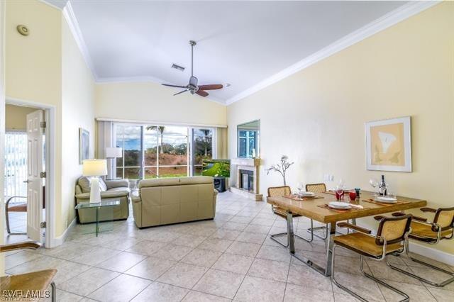 living room with high vaulted ceiling, crown molding, ceiling fan, and light tile patterned floors