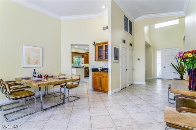 tiled entrance foyer with sink, a high ceiling, and crown molding