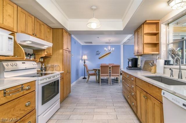 kitchen featuring hanging light fixtures, sink, white appliances, and a tray ceiling