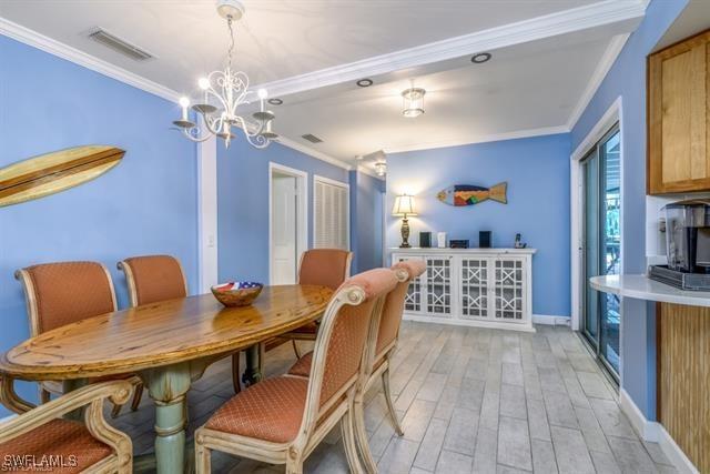 dining space featuring ornamental molding, light hardwood / wood-style floors, and a notable chandelier