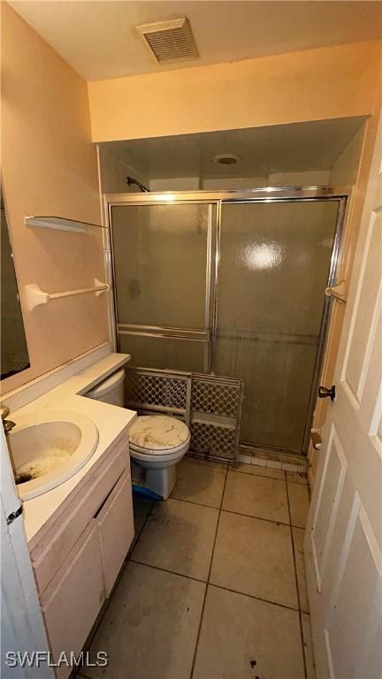 bathroom with tile patterned floors, vanity, toilet, and an enclosed shower