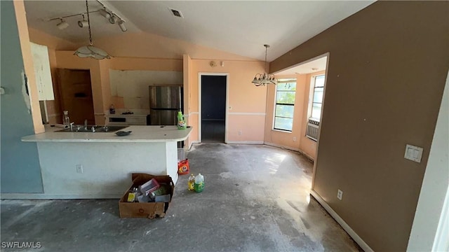 kitchen with sink, stainless steel fridge, hanging light fixtures, vaulted ceiling, and kitchen peninsula