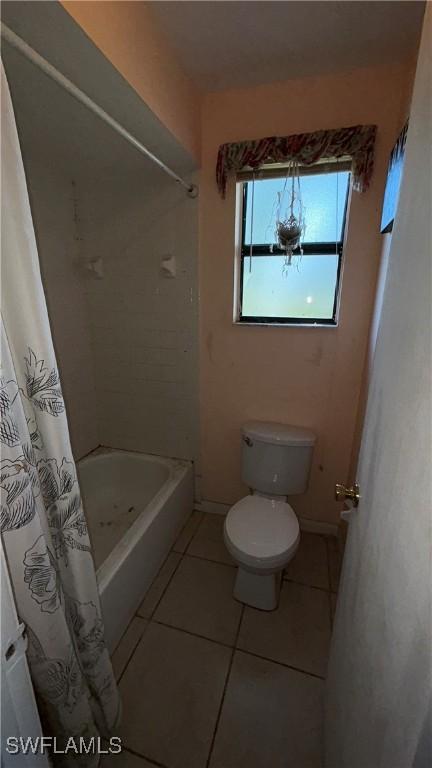 bathroom with tile patterned flooring, shower / bath combo, and toilet