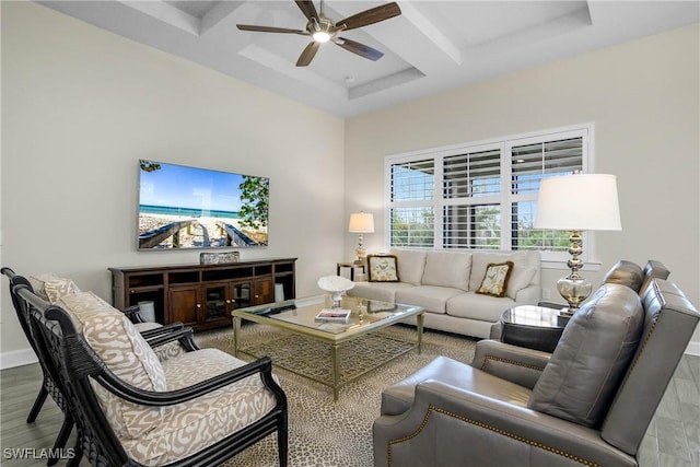 living room featuring a towering ceiling, beamed ceiling, coffered ceiling, ceiling fan, and light hardwood / wood-style flooring